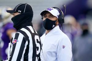 Washington coach Jimmy Lake stands with official Michael Weseloh as he waits for a review of a call during the second half of the team's NCAA college football game against Stanford on Saturday, Dec. 5, 2020, in Seattle. (AP Photo/Elaine Thompson)