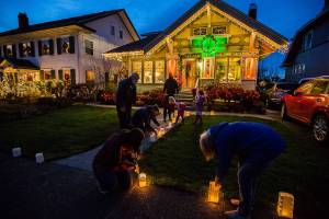 The McCoy Family, along with help from neighbors, light the luminaries lining their walkway along the 1200 block of Rucker on Thursday, Dec. 24, 2020 in Everett, Wa. (Olivia Vanni / The Herald)