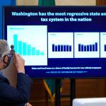 Gov. Jay Inslee looks toward a chart comparing Washington states tax system to other Western states as he talks to reporters, Thursday at the Capitol in Olympia. Inslee is proposing a new capital gains tax and a tax on health insurers as part of his two-year budget proposal that seeks to offset the revenue losses the state has seen during the ongoing coronavirus pandemic and to help bolster the states public health system. (Ted S. Warren / Associated Press)