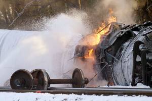 A firefighter sprays foam on a burning, derailed train car Tuesday, Dec. 22, 2020, in Custer, Wash. Officials say seven train cars carrying crude oil derailed and five caught fire north of Seattle and close to the Canadian border. Whatcom County officials said the derailment occurred in the downtown Custer area, where streets were closed and evacuations ordered during a large fire response. (AP Photo/Elaine Thompson)