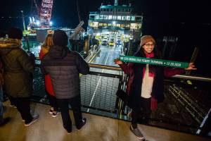 Sofia Samoyoa takes a photograph with a commemorative ribbon as the first car passengers to use the new Mukilteo ferry terminal offload on Tuesday, Dec. 29, 2020 in Mukilteo, Wa. (Olivia Vanni / The Herald)