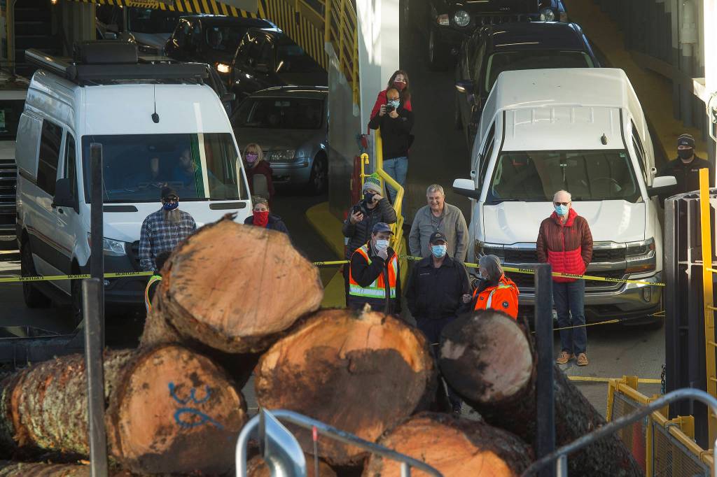 State ferry workers and passengers inspect the pile of logs blocking the ramp of the Edmonds ferry terminal. (Andy Bronson / The Herald)