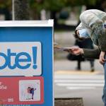 In this Oct. 28 photo, a voter eyes the opening of a ballot drop box before placing his ballot inside it in Seattle. A record number of voters participating in Novembers election was among Washington states top stories for 2020. (AP Photo/Elaine Thompson, File)