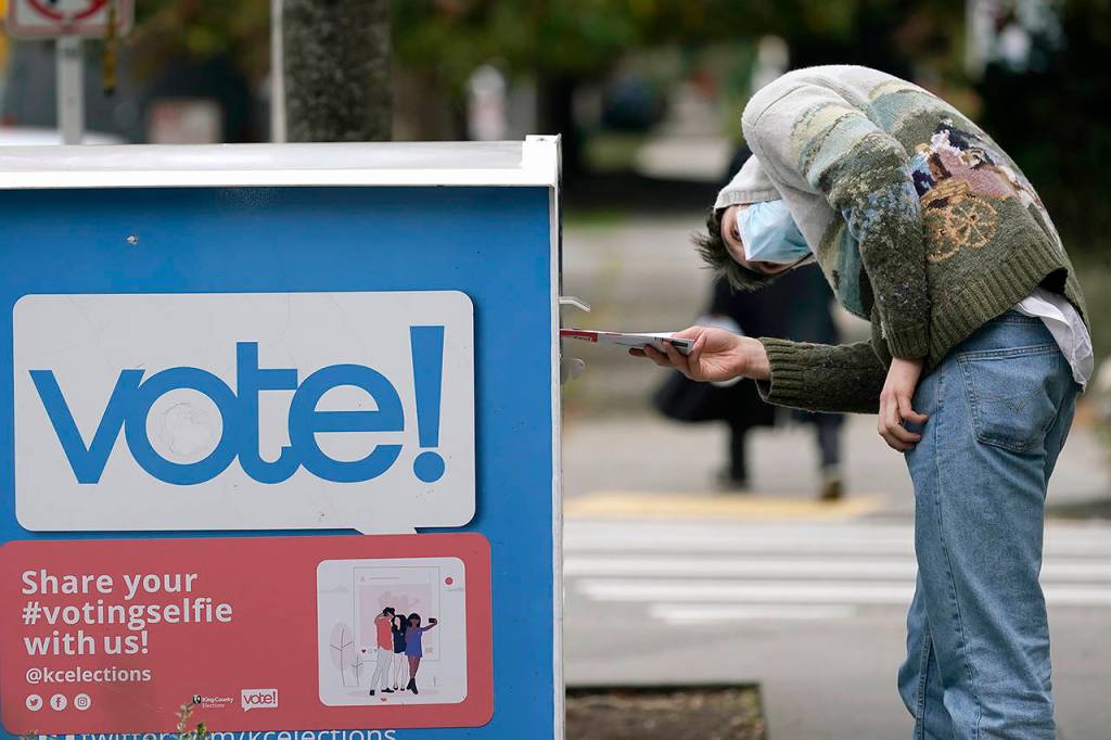 In this Oct. 28 photo, a voter eyes the opening of a ballot drop box before placing his ballot inside it in Seattle. A record number of voters participating in Novembers election was among Washington states top stories for 2020. (AP Photo/Elaine Thompson, File)