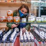 Store employee Cece Stafford arranges stock at Alchemy Health and Wellness CBD in Alderwood mall. (Kevin Clark / The Herald)