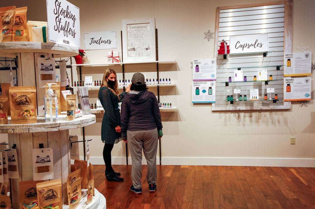 Store co-owner Jill Humphrey (left) helps a customer at Alchemy Health and Wellness CBD in Alderwood mall. (Kevin Clark / The Herald)