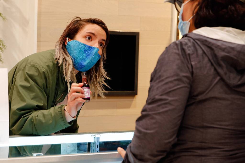Store employee Cece Stafford helps a customer at Alchemy Health and Wellness CBD in Alderwood mall. (Kevin Clark / The Herald)