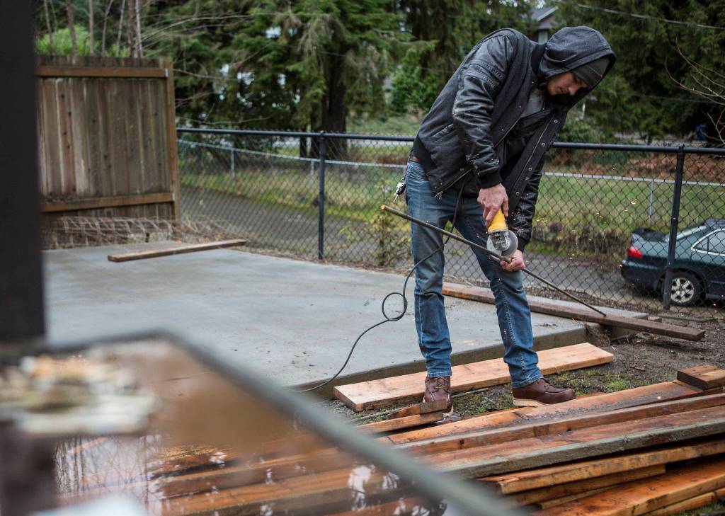 Dillon Carlson saws a piece of rebar for concrete being installed at a home in Lynnwood. (Olivia Vanni / The Herald)