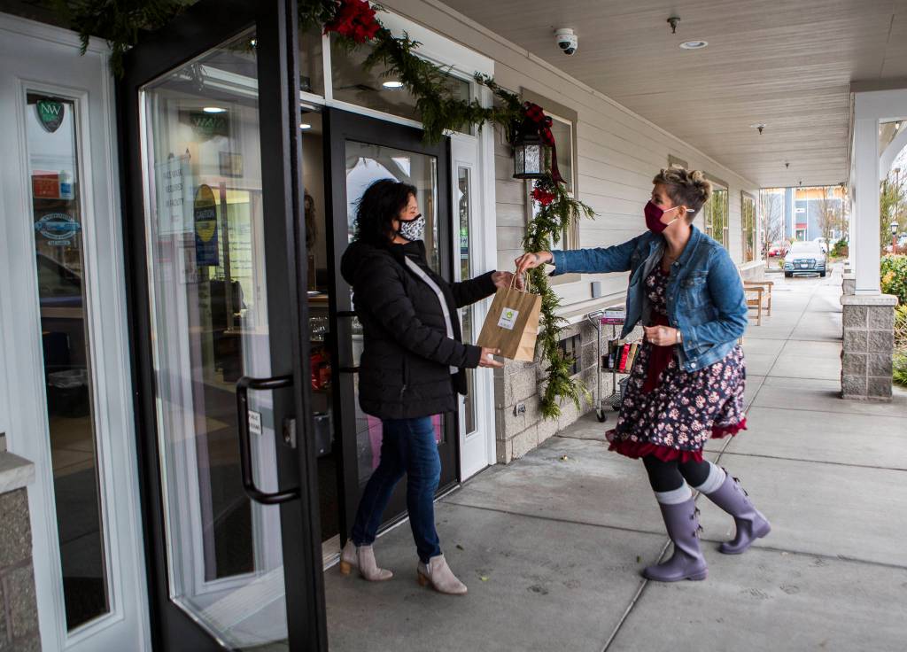 Snohomish Delivers concierge Sarah Dylan Jensen hands off a delivery to Snohomish Senior Center executive director Sharon Burlison on Tuesday in Snohomish. (Olivia Vanni / The Herald)