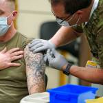 Staff Sgt. Travis Snyder (left) receives the first dose of the Pfizer vaccine for covid-19 given at Madigan Army Medical Center at Joint Base Lewis-McChord, Dec. 16, in Washington state. Nurse Jose Picart administered the shot. Vaccinations are scheduled to continue in the coming weeks for front-line medical workers and and others in high-priority positions at the base. (Ted S. Warren / Associated Press)