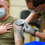 Staff Sgt. Travis Snyder, left, receives the first dose of the Pfizer vaccine for COVID-19 given at Madigan Army Medical Center at Joint Base Lewis-McChord, Wednesday, Dec. 16, 2020, in Washington state, south of Seattle. Nurse Jose Picart, right, administered the shot. Vaccinations are scheduled to continue in the coming weeks for front-line medical workers and and others in high-priority positions at the base. (AP Photo/Ted S. Warren)