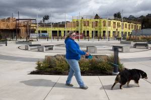 Amy Ulrich walks her dog Kahlua by the Waterfront Place Apartments at the Port of Everett on Monday, March 30, 2020 in Everett, Wa. Gov. Inslee ordered construction projects around the state to shut down for two weeks. That pauses several big housing projects at Alderwood and the Port. (Andy Bronson / The Herald)