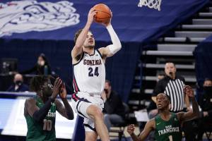 Gonzaga forward Corey Kispert (24) shoots between San Francisco forward Josh Kunen (10) and guard Jamaree Bouyea (1) during the first half of an NCAA college basketball game in Spokane, Wash., Saturday, Jan. 2, 2021. (AP Photo/Young Kwak)