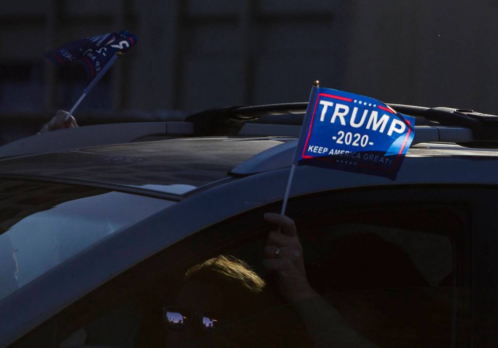 Trump supporters wave flags out of their car on Wednesday, Jan. 6, 2020 in Everett, Wa. (Olivia Vanni / The Herald)