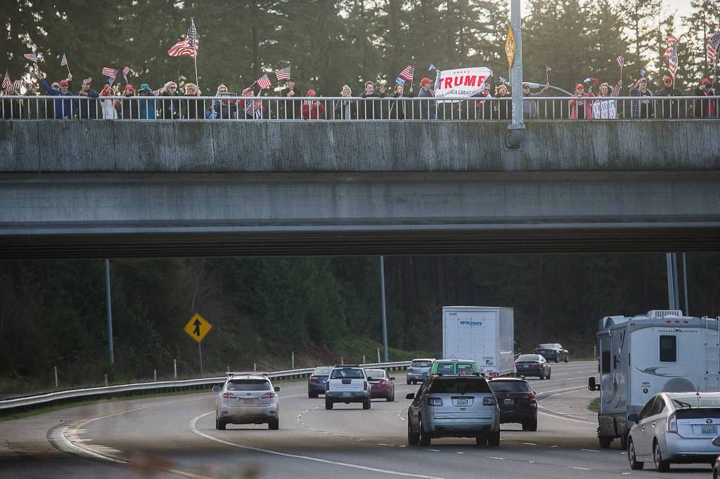 President Trump supporters wave flags and signs on the I-5 overpass at the 112th Street park-and-ride on Wednesday in Everett. (Andy Bronson / The Herald)