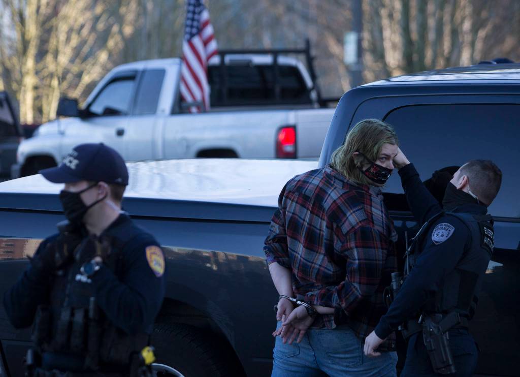 A man is briefly detained before being let go after an altercation with a Trump supporter in front of the Snohomish County Courthouse on Wednesday, Jan. 6, 2020 in Everett, Wa. (Olivia Vanni / The Herald)