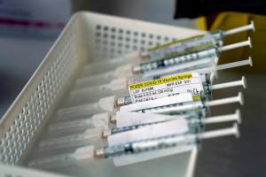FILE - In this Jan. 7, 2021, file photo syringes containing the Pfizer-BioNTech COVID-19 vaccine sit in a tray in a vaccination room at St. Joseph Hospital in Orange, Calif. Taking a new direction to speed release of coronavirus vaccines, President-elect Joe Biden's office said Friday he would end the current practice of holding back vaccine doses to guarantee that people who get their first shot can also get a required second inoculation three weeks later. (AP Photo/Jae C. Hong, File)