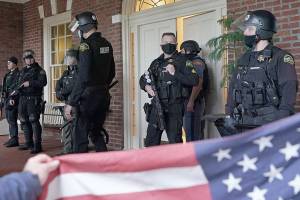 Protesters square off with law enforcement officers on the front porch of the Governor's Mansion after a group of people got through a perimeter fence, Wednesday, Jan. 6, 2021, at the Capitol in Olympia, Wash., following a protest against the counting of electoral votes in Washington, DC, affirming President-elect Joe Biden's victory. The area was eventually cleared by police. (AP Photo/Ted S. Warren)