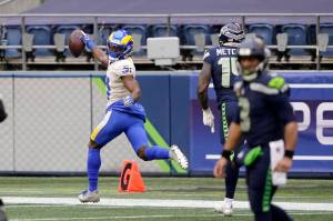 Los Angeles Rams defensive back Darious Williams (31) looks back as he scores on an interception from Seattle Seahawks quarterback Russell Wilson, right, during the first half of Sundays playoff game at Lumen Field. (AP Photo/Ted S. Warren)