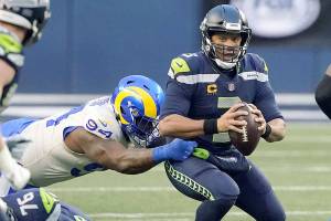 Seattle Seahawks quarterback Russell Wilson, right, eyes a receiver as Los Angeles Rams defensive tackle A'Shawn Robinson grabs him during the second half of an NFL wild-card playoff football game, Saturday, Jan. 9, 2021, in Seattle. (AP Photo/Ted S. Warren)
