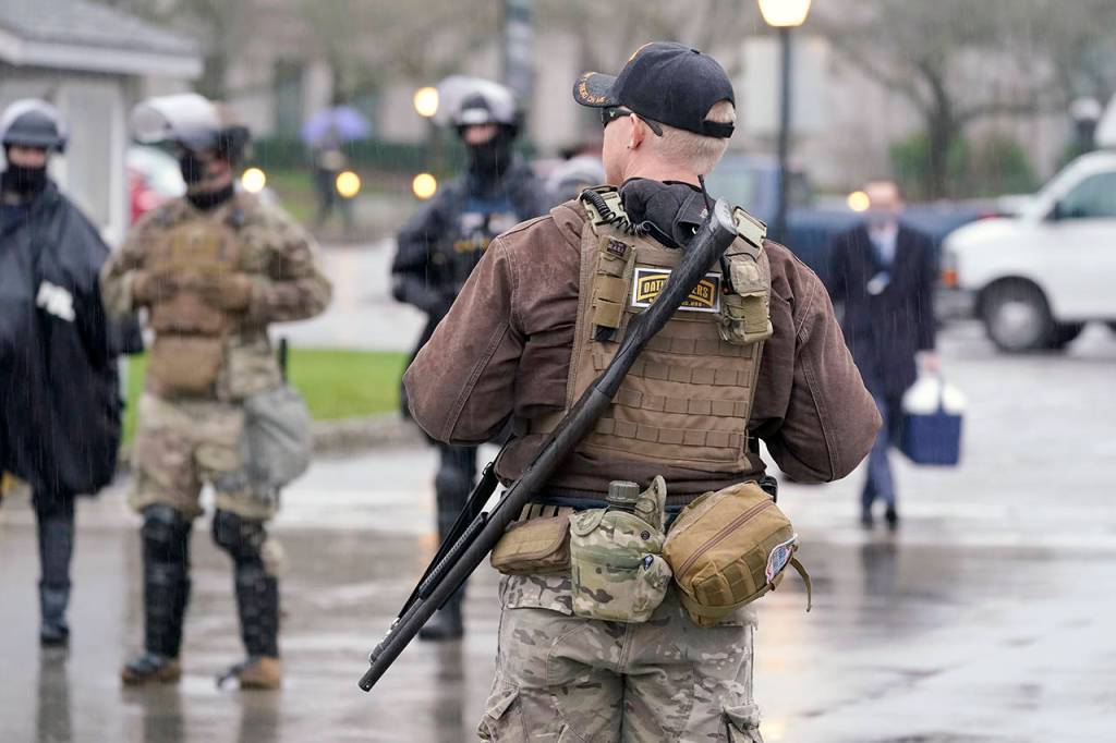 An armed protester stands outside the Capitol Monday in Olympia. According to organizers, some protesters are unhappy the Legislature will meeting virtually and in sessions not open to the public, due to the COVID-19 pandemic, during the 2021 session which opens Monday. (AP Photo/Ted S. Warren)