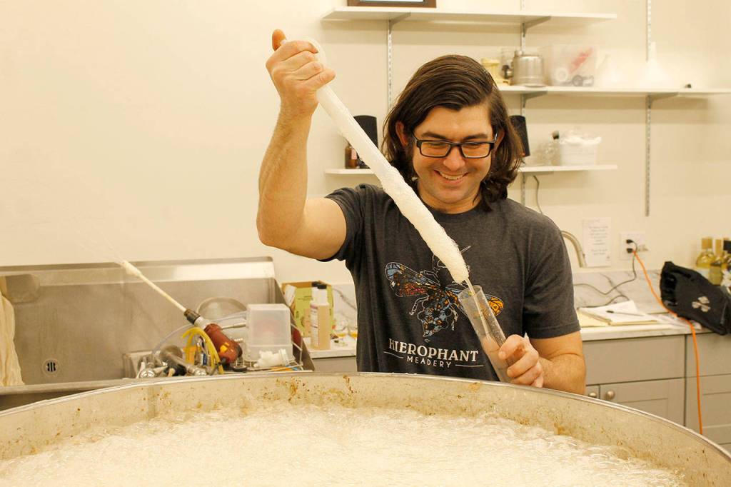 Jeremy Kyncl fills a beaker with mead hes making at Hierophant Meadery in Freeland. (Kira Erickson/South Whidbey Record)