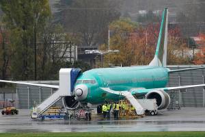 FILE - In this Wednesday, Nov. 18, 2020 file photo, workers stand near a Boeing 737 Max airplane parked at Renton Municipal Airport next to the Boeing assembly facility in Renton, Wash., where 737 Max airplanes are made. On Tuesday, Jan. 12, 2021, the company reported final 2020 numbers for airplane orders and deliveries, and they are down from 2019 even though the 737 Max is flying again. (AP Photo/Ted S. Warren)