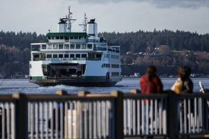 People watch as a full ferry boat leave the Mukilteo Ferry Terminal on Tuesday, Dec. 22, 2020 in Mukilteo, Wa. (Olivia Vanni / The Herald)