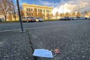 A discarded face mask lies on the sidewalk across the street from Everett High School last December. (Sue Misao / The Herald)
