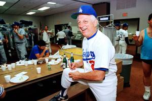FILE - Los Angeles Dodgers manager Tommy Lasorda autographs a baseball in the Dodgertown locker-room in Vero Beach, Fla., in this Wednesday, Feb. 15, 1990, file photo. Tommy Lasorda, the fiery Hall of Fame manager who guided the Los Angeles Dodgers to two World Series titles and later became an ambassador for the sport he loved during his 71 years with the franchise, has died. He was 93. The Dodgers said Friday, Jan. 8, 2021, that he had a heart attack at his home in Fullerton, California. Resuscitation attempts were made on the way to a hospital, where he was pronounced dead shortly before 11 p.m. Thursday.  (AP Photo/Richard Drew, File)