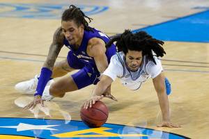 Washington forward Hameir Wright, left, and UCLA guard Tyger Campbell dive for a loose ball during the second half of an NCAA college basketball game Saturday, Jan. 16, 2021, in Los Angeles. (AP Photo/Ashley Landis)