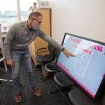 Athletic Director Tom Wilfong demonstrates a touchscreen display that will replace many of the plaques and photos that list school academic and sports records. (Andy Bronson / The Herald)