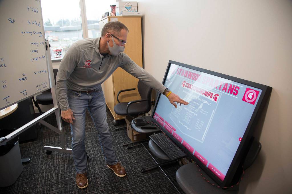 Athletic Director Tom Wilfong demonstrates a touchscreen display that will replace many of the plaques and photos that list school academic and sports records. (Andy Bronson / The Herald)