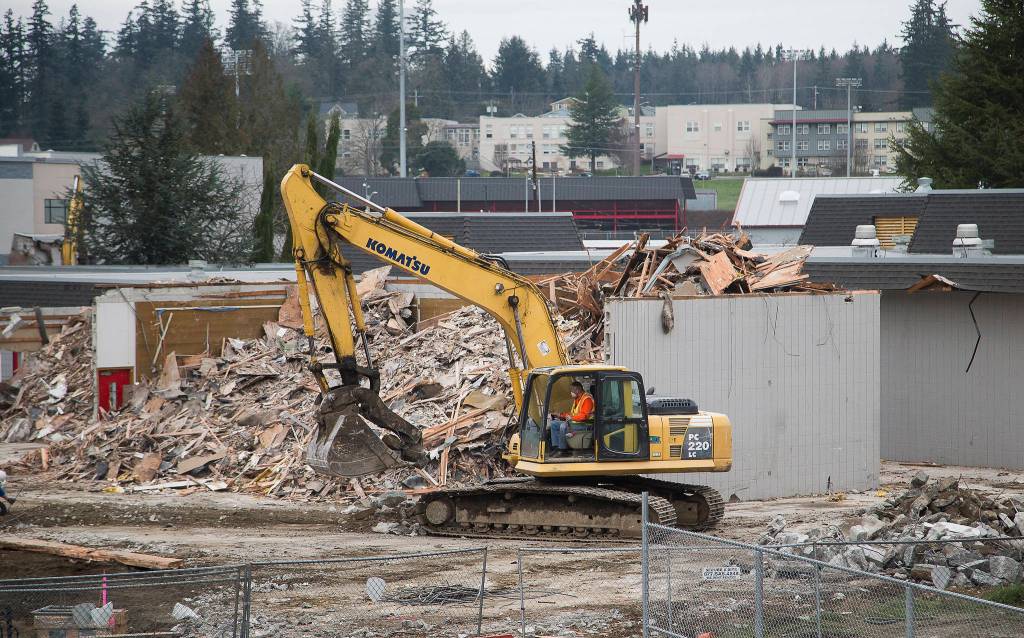 A view from a classroom in the new Stanwood High School shows crews tearing down parts of the old building, built in 1971, on Wednesday. (Andy Bronson / The Herald)