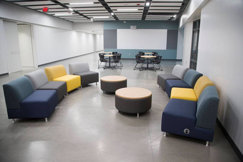 Cushioned chairs with charging ports are near walls made of whiteboards in the hallways outside of classrooms. (Andy Bronson / The Herald)