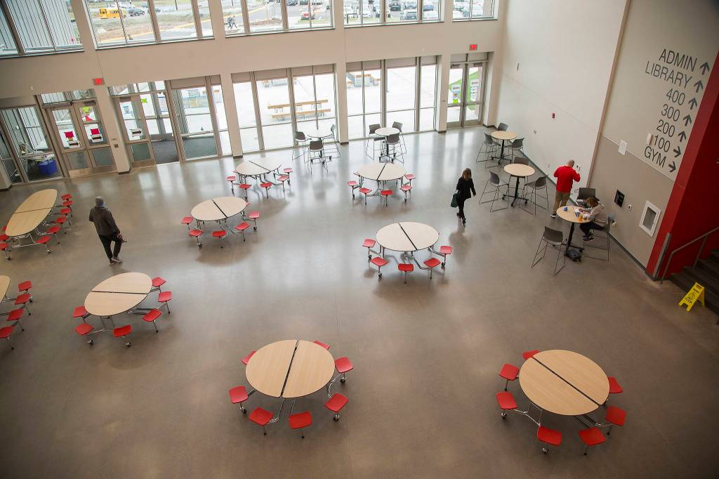 Staff walk through the commons and cafeteria Wednesday in the new Stanwood High School. (Andy Bronson / The Herald)