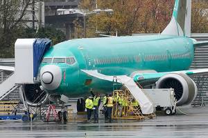 FILE - In this Wednesday, Nov. 18, 2020 file photo, workers stand near a Boeing 737 Max airplane parked at Renton Municipal Airport next to the Boeing assembly facility in Renton, Wash., where 737 Max airplanes are made. On Tuesday, Jan. 12, 2021, the company reported final 2020 numbers for airplane orders and deliveries, and they are down from 2019 even though the 737 Max is flying again. (AP Photo/Ted S. Warren)