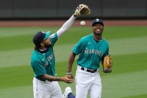 Seattle Mariners J.P. Crawford, left, and Kyle Lewis run together off the field against the Oakland Athletics in a baseball game during the Mariners home opener Friday, July 31, 2020, in Seattle. (AP Photo/Elaine Thompson)