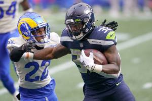 Seattle Seahawks running back Chris Carson (32) carries as Los Angeles Rams cornerback Troy Hill defends during the first half of an NFL wild-card playoff football game, Saturday, Jan. 9, 2021, in Seattle. (AP Photo/Ted S. Warren)