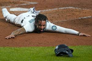 Seattle Mariners shortstop J.P. Crawford sprawls on the dirt and reacts after sliding safely home during the fifth inning of a baseball game against the Houston Astros, Wednesday, Sept. 23, 2020, in Seattle. Crawford scored on a double hit by Kyle Seager. (AP Photo/Ted S. Warren)