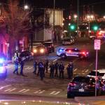 Tacoma Police and other law enforcement officers stand in an intersection near the site of a car crash Saturday in downtown Tacoma. At least one person was injured when a police car plowed through a crowd of people Saturday night who were watching a downtown street race, the Tacoma News-Tribune reported. (AP Photo/Ted S. Warren)