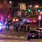 Tacoma Police and other law enforcement officers stand in an intersection near the site of a car crash Saturday, Jan. 23, 2021, in downtown Tacoma, Wash. At least one person was injured when a police car plowed through a crowd of people Saturday night who were watching a downtown street race, the Tacoma News-Tribune reported. (AP Photo/Ted S. Warren)
