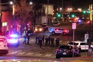 Tacoma Police and other law enforcement officers stand in an intersection near the site of a car crash Saturday, Jan. 23, 2021, in downtown Tacoma, Wash. At least one person was injured when a police car plowed through a crowd of people Saturday night who were watching a downtown street race, the Tacoma News-Tribune reported. (AP Photo/Ted S. Warren)