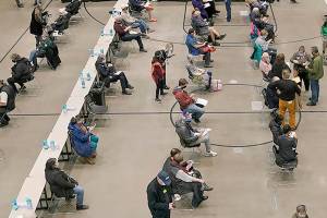 People are given the first of two doses of the Pfizer vaccine for COVID-19, Sunday, Jan. 24, 2021, at a one-day vaccination clinic set up in an Amazon.com facility in Seattle and operated by Virginia Mason Franciscan Health. (AP Photo/Ted S. Warren)