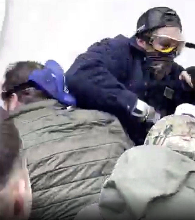 In this frame from video, Daniel Scott (left, in green jacket) can be seen at the front of a mob trying to storm the U.S. Capitol steps on Jan. 6 in Washington, D.C.