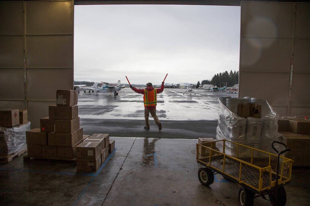 A volunteer directs a plane to a spot where it can be loaded with PPE supplies for an airlift to Native American tribes in Washington. (Andy Bronson / The Herald)