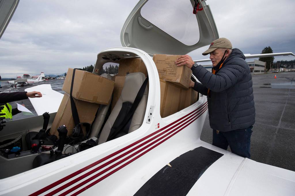 Pilot Greg Bell loads boxes into his Diamond DA-40 plane at Arlington Municipal Airport on Thursday. (Andy Bronson / The Herald)