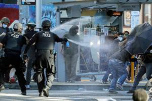 FILE - In this July 25, 2020, file photo, police pepper spray protesters, near Seattle Central College in Seattle, during a march and protest in support of Black Lives Matter. Washington state lawmakers and activists are setting an ambitious agenda for police reform in the upcoming legislative session. They say they hope to make it easier to decertify officers for misconduct, to bar the use of police dogs to make arrests, and to create an independent statewide agency to investigate police killings. (AP Photo/Ted S. Warren, File)