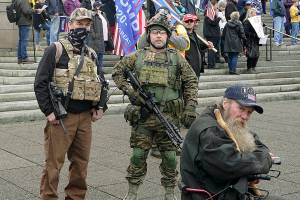 In this photo taken Jan. 6, 2021 at the Capitol in Olympia, Wash., two men stand armed with guns at a protest supporting President Donald Trump and against the counting of electoral votes in Washington, DC, affirming President-elect Joe Biden's victory. The open carry of guns and other weapons would be banned on the Washington state Capitol campus and at or near any public demonstration across Washington under a measure that received a remote public hearing Tuesday, Jan. 26, 2021 by the Senate Law and Justice Committee. (AP Photo/Ted S. Warren)