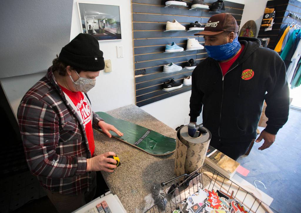 Ben Coer (left) helps a customer with a new skateboard. (Olivia Vanni / The Herald) 
